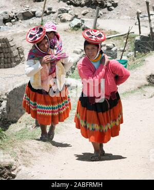 Patachancha, Cuzco, Perù - Ottobre 21, 2012 : sorridere le donne indigene camminare in salita. Uno di loro portando il suo bambino In una imbracatura Foto Stock