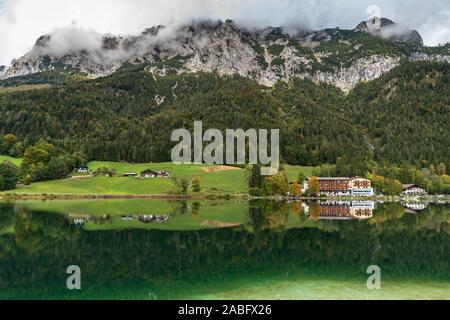 Visione idilliaca di Hintersee con bellissimi riflessi di alberi e le case e le Alpi in background, vicino lago Konigssee, Ramsau in Berchtesgaden, BAV Foto Stock