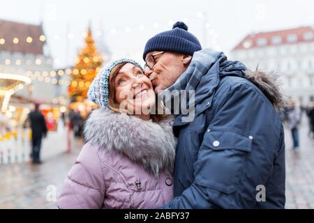 Felice coppia senior kissing al mercatino di natale Foto Stock