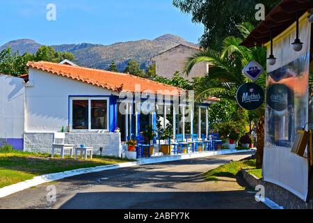 Una bella scena di strada di Maria del ristorante sulla strada principale attraverso questo bellissimo villaggio sul mare con uno sfondo di montagne al sole. Foto Stock