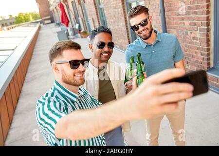 Gli uomini di bere birra e tenendo selfie tramite smartphone Foto Stock