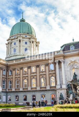 Budapest, Ungheria - Novembre 6, 2019: il Castello di Buda con fontana monumentale gruppo noto come Matthias Fontana nel cortile. Facciata con pilastri, finestre ad arco e cupola. I turisti sulla piazza. Foto Stock