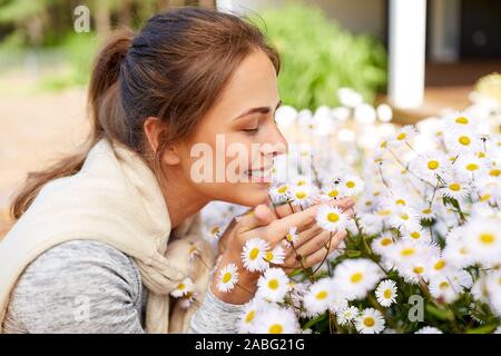 Donna felice odorare i fiori di camomilla in giardino Foto Stock