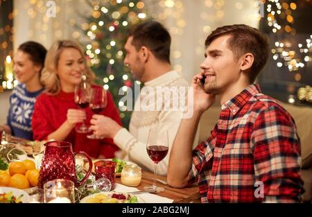 L'uomo chiamando sullo smartphone a cena di natale Foto Stock