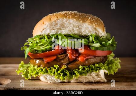 Vegan burger con seitan e verdure su un tavolo di legno. Fake carne. Foto Stock