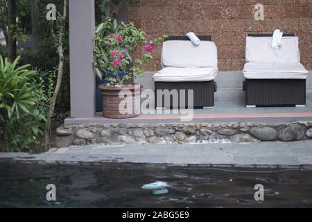 Lettini con materassini e asciugamani a bordo della piscina sulla terrazza dell'hotel Foto Stock