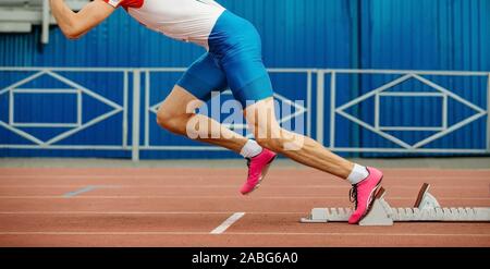 Avviare sprint in esecuzione dai blocchi di partenza atleta maschio Foto Stock