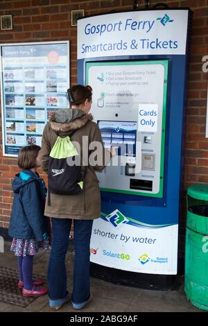 Donna / passeggero Madonna con bambino acquistando i biglietti da un solo carte di biglietteria automatica per se stessa e a sua figlia di viaggiare a Portsmouth sulla Gosport Ferry in Hampshire. Regno Unito (105) Foto Stock