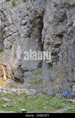 Malham Cove,Skipton, Yorkshire/Regno Unito 11 Settembre 2014: una persona salire la Malham roccia durate tre altri guardano da sotto. Foto Stock