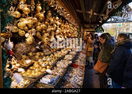Vienna, Austria - 11.23.2019 : donne giovani turisti ammirando appeso golden ornamento di Natale decorazione stand kiosk su un mercato invernale rathausplatz Foto Stock