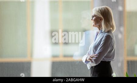 Sorridente di mezza età imprenditrice guardare nel pensiero di distanza Foto Stock