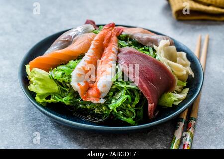 Sashimi con insalata di Wakame, alghe, salmone, spigola, gamberetti, Kani, sgombro pesce, tonno servita con bacchette. Tradizionale cibo organico. Foto Stock