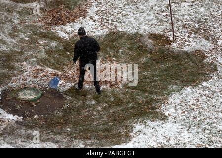 Un dipendente di utilità rimuove il fogliame sulla zona locale nella città di Mosca durante la prima neve, Russia Foto Stock