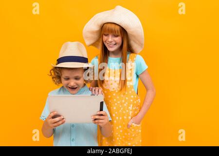 Due giovani i capelli rossi amici con cappelli estivi scelto pacchetti vacanza isolato sfondo giallo Foto Stock