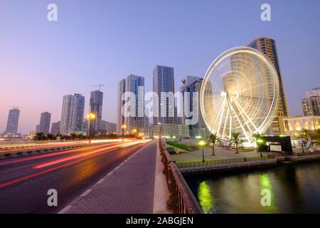 Vista serale dell'occhio degli Emirati ruota panoramica Ferris a Al Qasba e sullo skyline di Sharjah Emirati Arabi Uniti Foto Stock