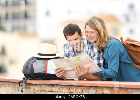 Felice coppia di turisti controllo mappa in vacanza in piedi all'aperto in un balcone in un paese rurale Foto Stock