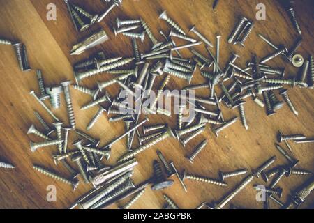 Tipi e formati diversi di chiodi e viti su un tavolo di legno Foto Stock