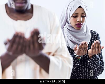 Musulmani africani giovane pregare Allah alzando le mani e rendendo fatiha pregare isolati su sfondo bianco Foto Stock