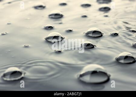 Bolle sulla liscia superficie di acqua nel giorno di pioggia, closeup, spazio di copia Foto Stock