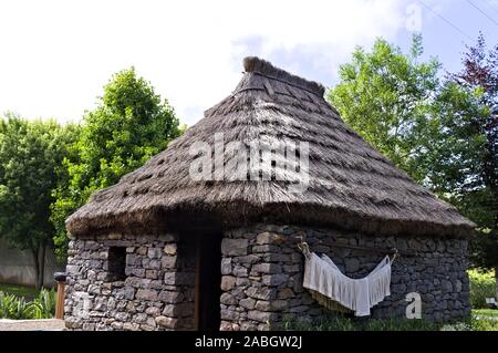 Vecchia casa di Santana in Isola di Madeira in pietra con il tetto di paglia. Alcuni vestiti di bianco sono appesi al muro. (Santana, Madeira, Portogallo) Foto Stock