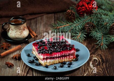 Fetta di Natale cheesecake con riempimento di ribes nero su una tavola in legno rustico Foto Stock