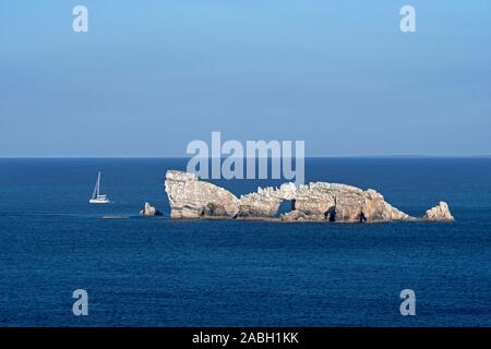 Barca a vela passando il Rocher du Lion rock con arco naturale visto dal Pointe de Pen Hir, Crozon Peninsula, Finistère Bretagna, Francia Foto Stock