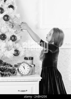 Bambino festeggiano il Natale a casa. Giorno preferito dell'anno. Celebrazione della Messa di Natale. Ottenere incredibilmente entusiasti di natale. Kid ragazza albero di natale in attesa della mezzanotte orologio. Infanzia felicità concetto. Foto Stock