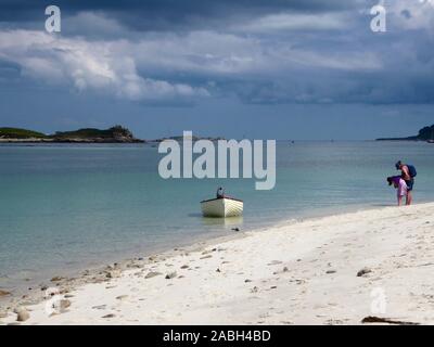 La spiaggia di Samson e, di fronte alle Flats, Carn Vicino a Tresco, Isles of Scilly, Inghilterra, Regno Unito. Due vacanzieri e il loro gommone: Rilasciato il modello Foto Stock