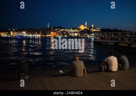 Istanbul: uomini ammirando lo skyline di notte sul Golden Horn e Moschea Suleymaniye Ottoman Imperial moschea commissionata dal sultano Solimano il Magnifico Foto Stock