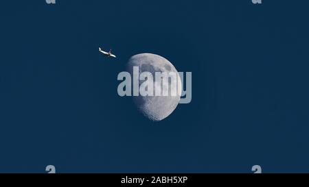 Aeroplano passando la luna crescente di sera la luce diurna Foto Stock