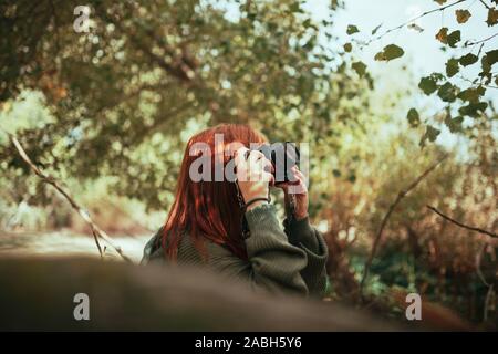 Giovane donna di scattare le foto nella foresta con una vecchia telecamera analogica Foto Stock