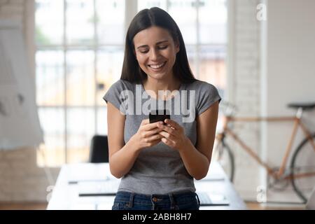 Colpo alla testa felice lavoratrice in abiti casual utilizza lo smartphone. Foto Stock