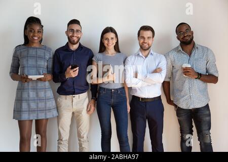 Felice fiducioso di successo dei lavoratori multietnica in piedi vicino a parete. Foto Stock