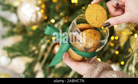 I cookies di avena in un vasetto di vetro. Contro lo sfondo delle decorazioni di Natale e albero di Natale in verde e il colore dell'oro Foto Stock