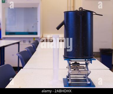 Schizzando può con la provetta di acqua per misurare la densità di un oggetto irregolare. Volume di liquido in millilitri. Esame pratico Foto Stock