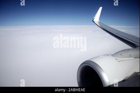 Mare di nuvole bianche visto dalla finestra di un aereo commerciale da cui l'ala destra motore è visibile Foto Stock