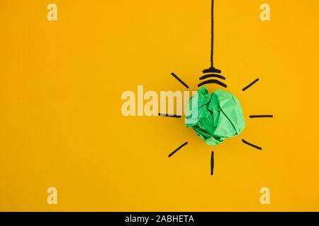 Crumpled libro verde lampadina luce su sfondo giallo. Close up. Foto Stock