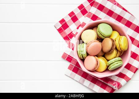 Dolce macarons colorati nella ciotola sul tavolo bianco. Vista dall'alto. Foto Stock