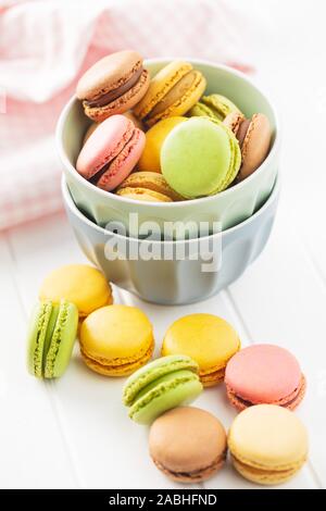 Dolce macarons colorati nella ciotola sul tavolo bianco. Foto Stock