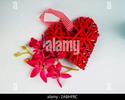 Sfondo con fiori e decorativo cuore rosso nel raggio di luce blu. Messa a fuoco selettiva è sul cuore. Posto per il testo. Il giorno di San Valentino, MOM, amore e Foto Stock