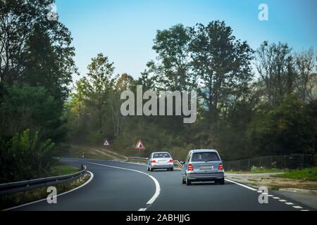 Vista posteriore di due vetture della guida su due strada attraverso la foresta di Gorski Kotar in Croazia. Foto Stock