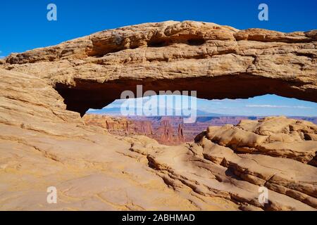 Un arco di pietra arenaria crea la finestra perfetta al canyon colorato sotto nel Parco Nazionale di Canyonlands Foto Stock