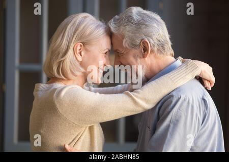 Anziani allegro giovane abbracciando guarda a vicenda con amore Foto Stock