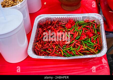 Hot peperoni rossi e verdi in una teglia di alluminio ad una notte di mercato Foto Stock