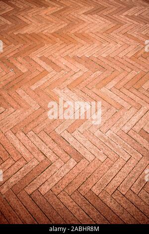 Mattoni di colore arancione pavimento piastrellato con andamento a zig-zag texture dello sfondo. Foto Stock