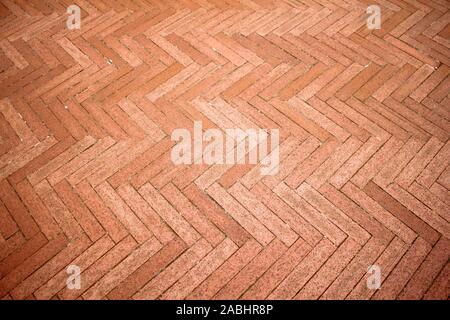 Mattoni di colore arancione pavimento piastrellato con andamento a zig-zag texture dello sfondo. Foto Stock