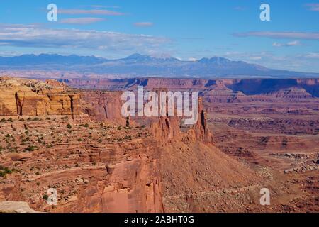 Esaminando la espansiva di Red Rock Canyon del Parco Nazionale di Canyonlands con montagne coperte di neve in background. Foto Stock