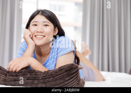 Asian teen felice vacanza sorridente posa sul letto del buon vivere sano a casa pulire camera da letto. Foto Stock