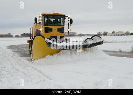 Un membro della 185th Air Refuelling ala rimozione neve team utilizza un grande Oshkosh H di serie aratro per cancellare neve dall'area della rampa a Sioux City, Iowa di base aria unità di guardia il 27 novembre 2019. L'apparecchiatura è specificamente progettato per l'uso in aeroporto. Stati Uniti Air National Guard foto di: Senior Master Sgt. Vincent De Groot Foto Stock