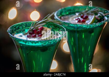 Champagne flauti close up, tenere la spumeggiante bevanda alcolica, guarnito con una fetta di lime, i semi di melograno e un rametto di rosmarino Foto Stock